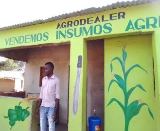 Man standing outside a newly painted agrodealer shop advertising agricultural inputs in Mozambique