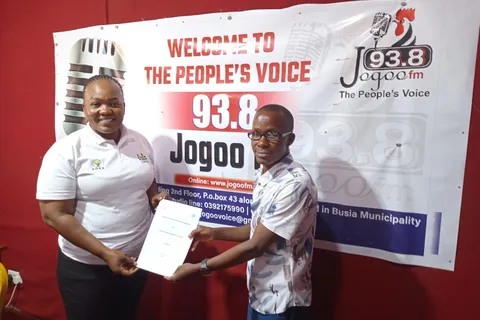 AGMARK and Jogoo FM representatives exchanging a signed partnership document in front of the radio station's banner