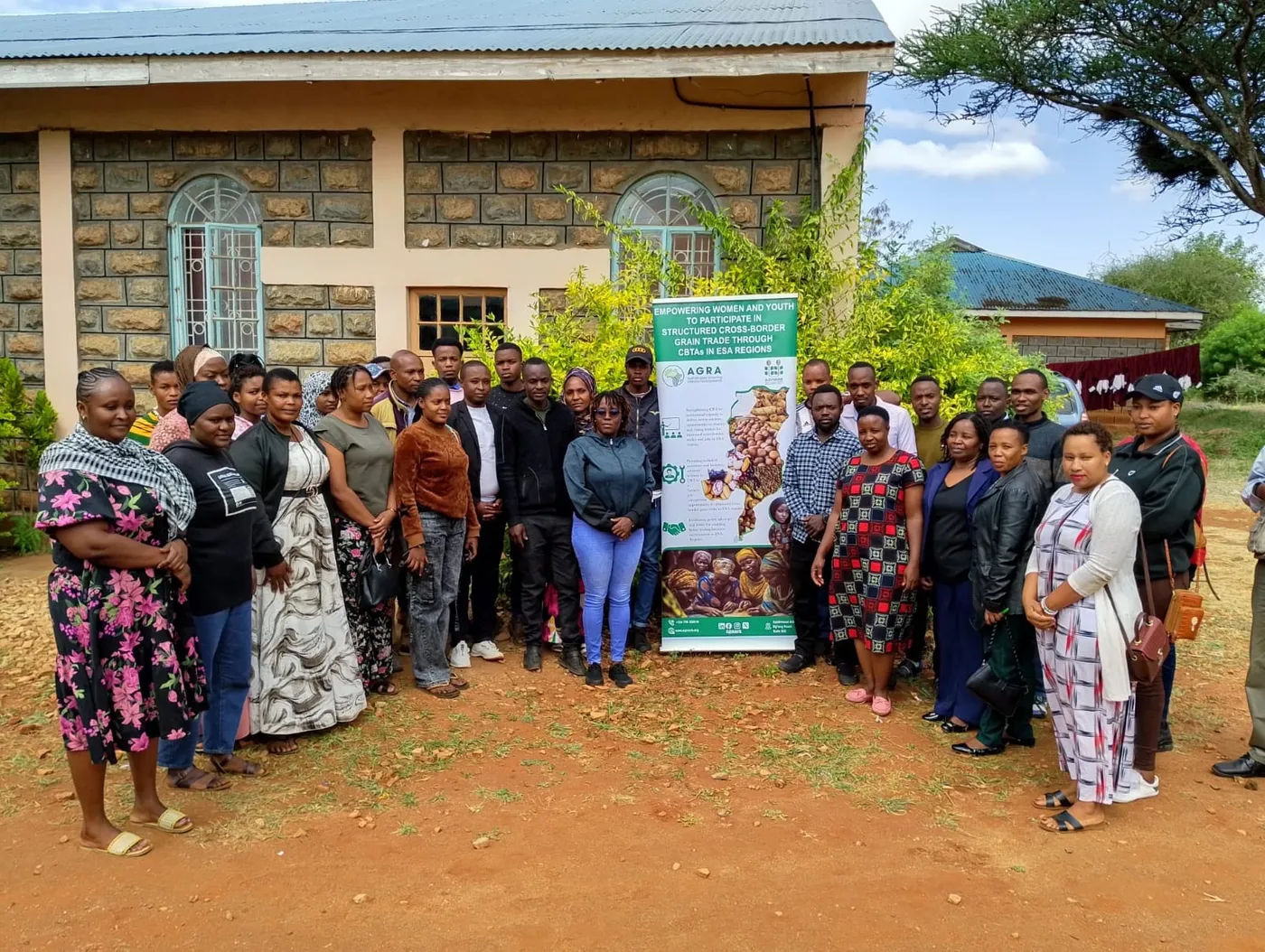 Group photo of youth and women grain trade trainees outside a training venue in Namanga