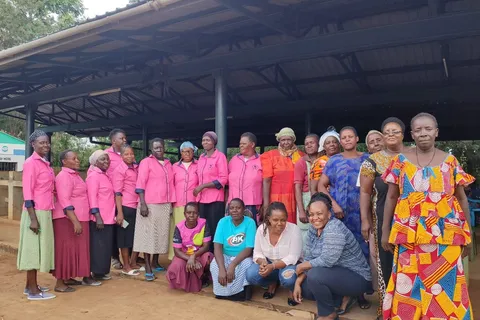 Group of women traders in matching pink uniforms posing under a pavilion