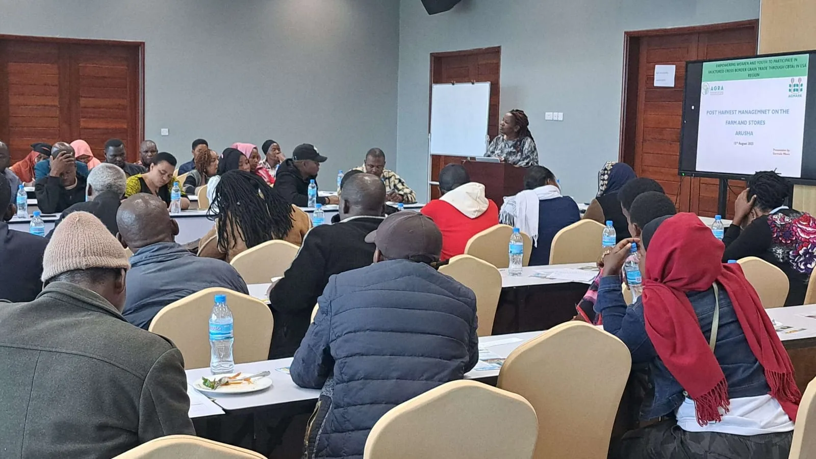 Attendees at Arusha seminar listening to speaker on post-harvest management; mixed attire; focus on empowering agriculture