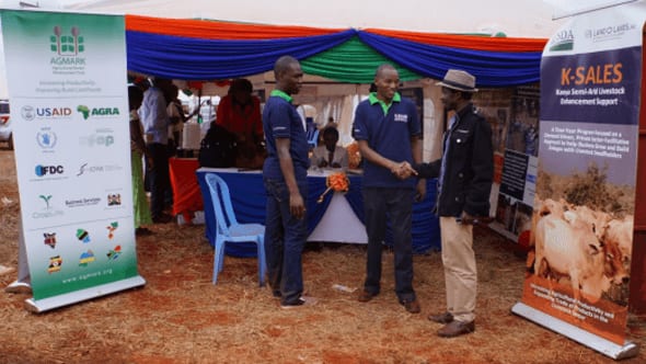 AGMARK representatives meet with a partner at Kenya semi-arid livestock enhancement K-SALES event, surrounded by exhibition booths